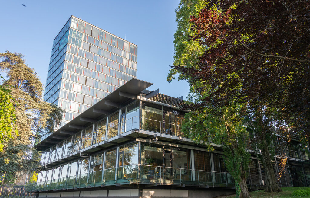 The outside of the UN conference building in Bonn with big glass windows, surrounded by trees.